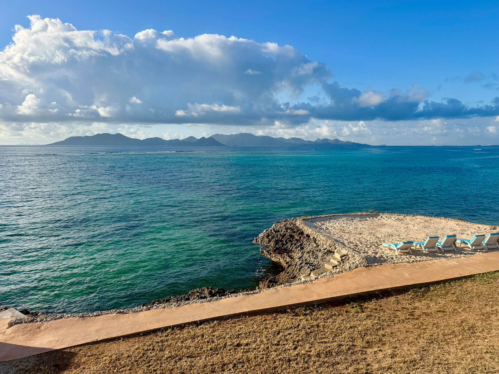 Villa Bénie outdoor terrace — shaded dining area, natural materials, ocean view